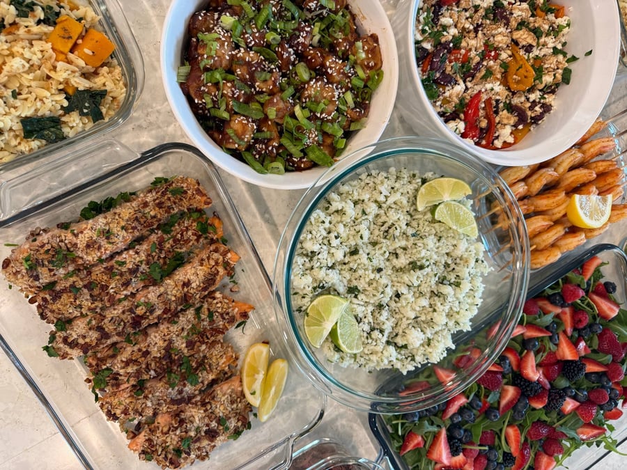 Six bamboo skewers of paprika-lime shrimp curl around a lemon wedge, cilantro rice and berry salad behind.