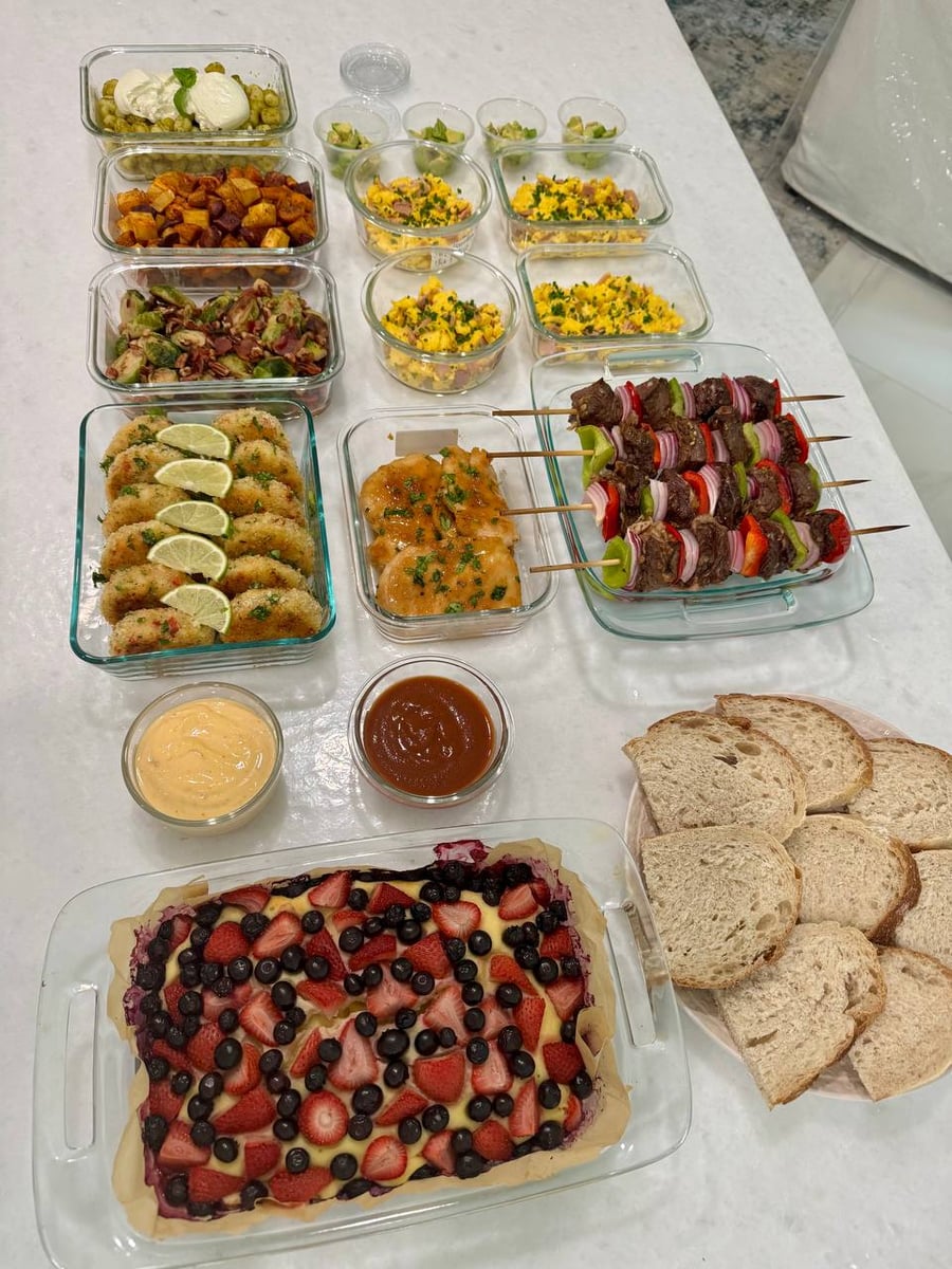 Everything on the white counter: kebobs, shrimp cakes, scrambled eggs, gnocchi and a berry bake.