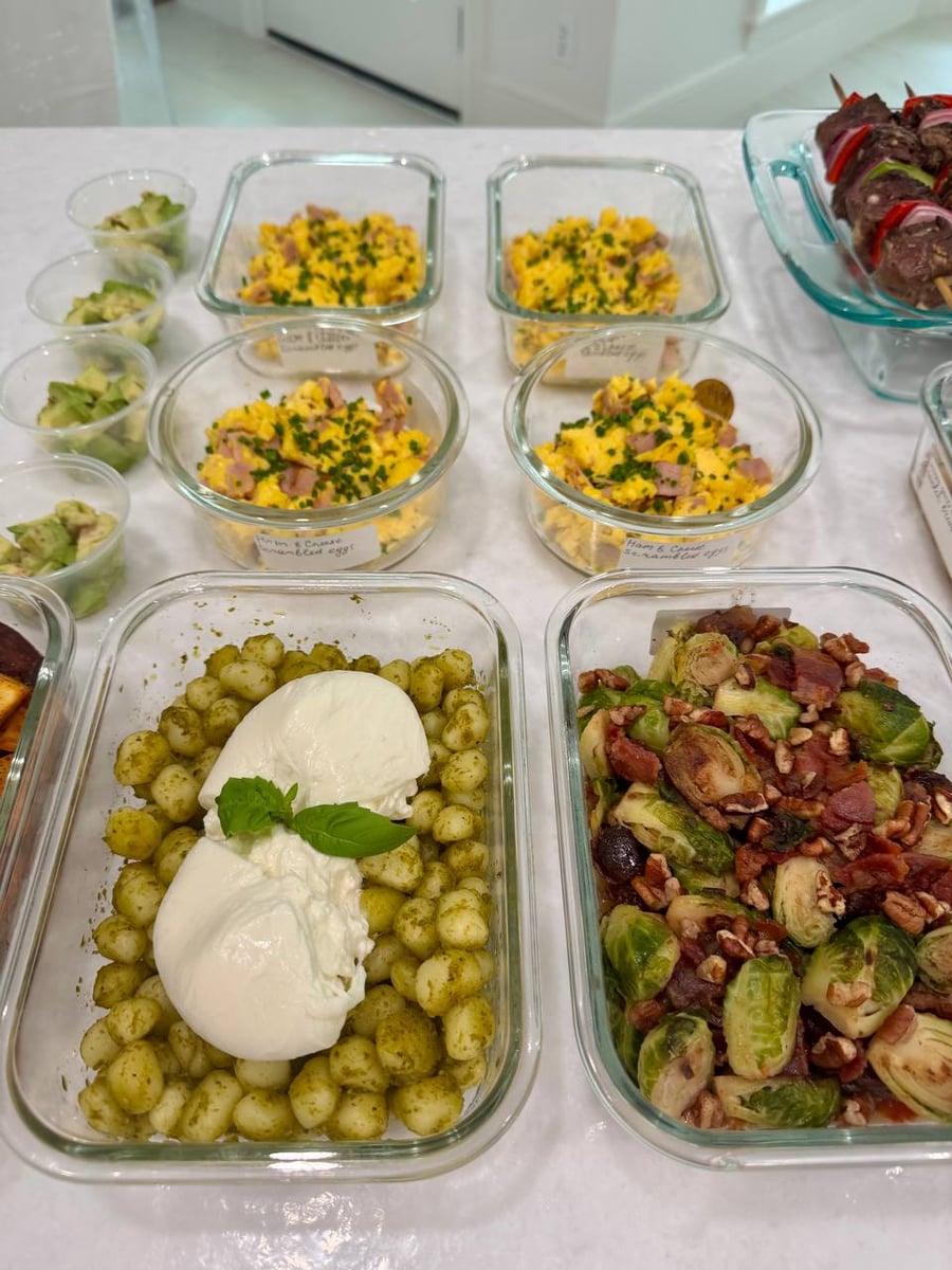 A basil sprig tops the burrata sunk into pesto gnocchi, bacon brussel sprouts to the right.