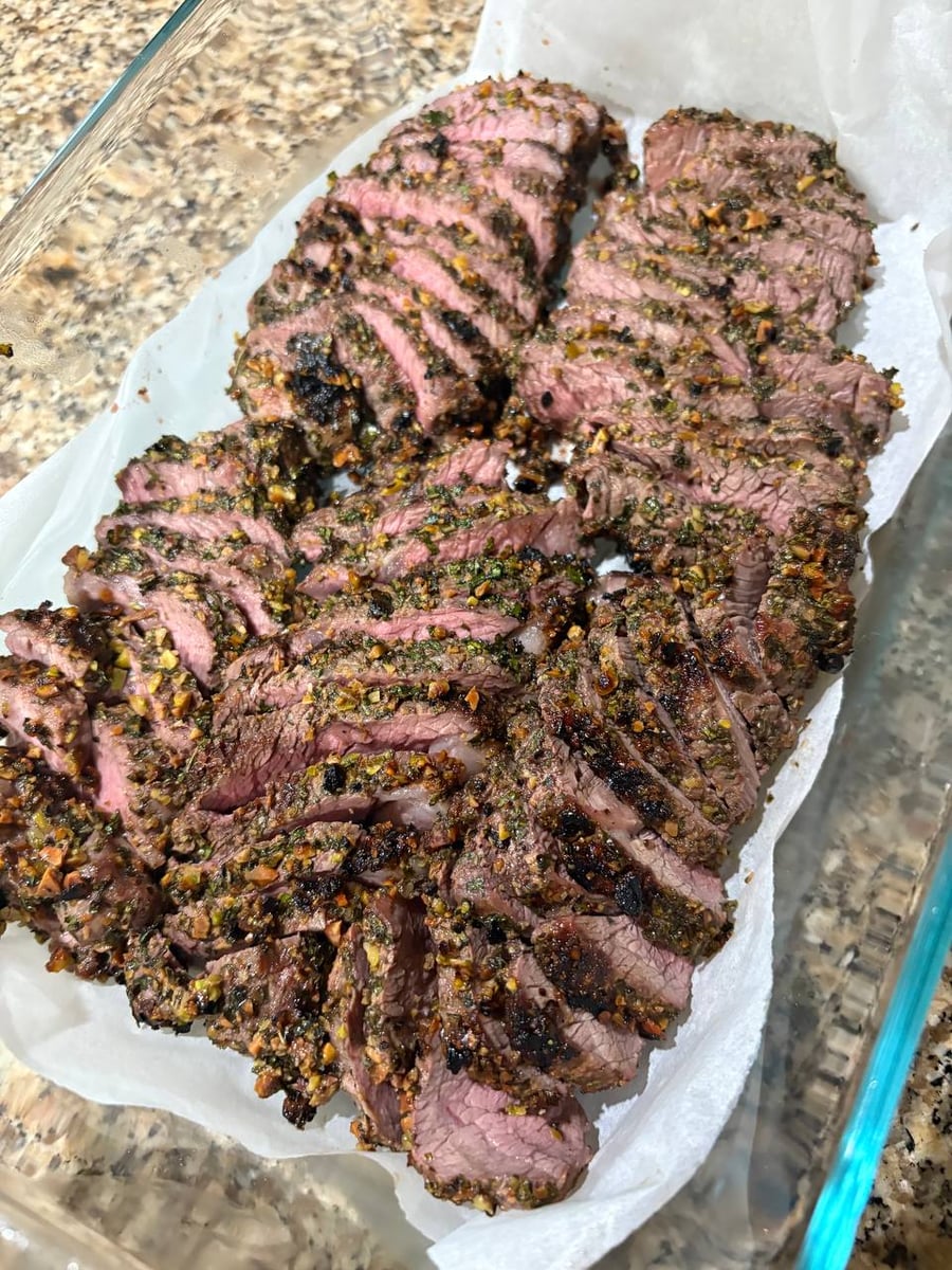 These perfectly grilled lamb chops are expertly sliced to showcase a tender, rose-colored interior and a distinctively textured mint and pistachio crust.