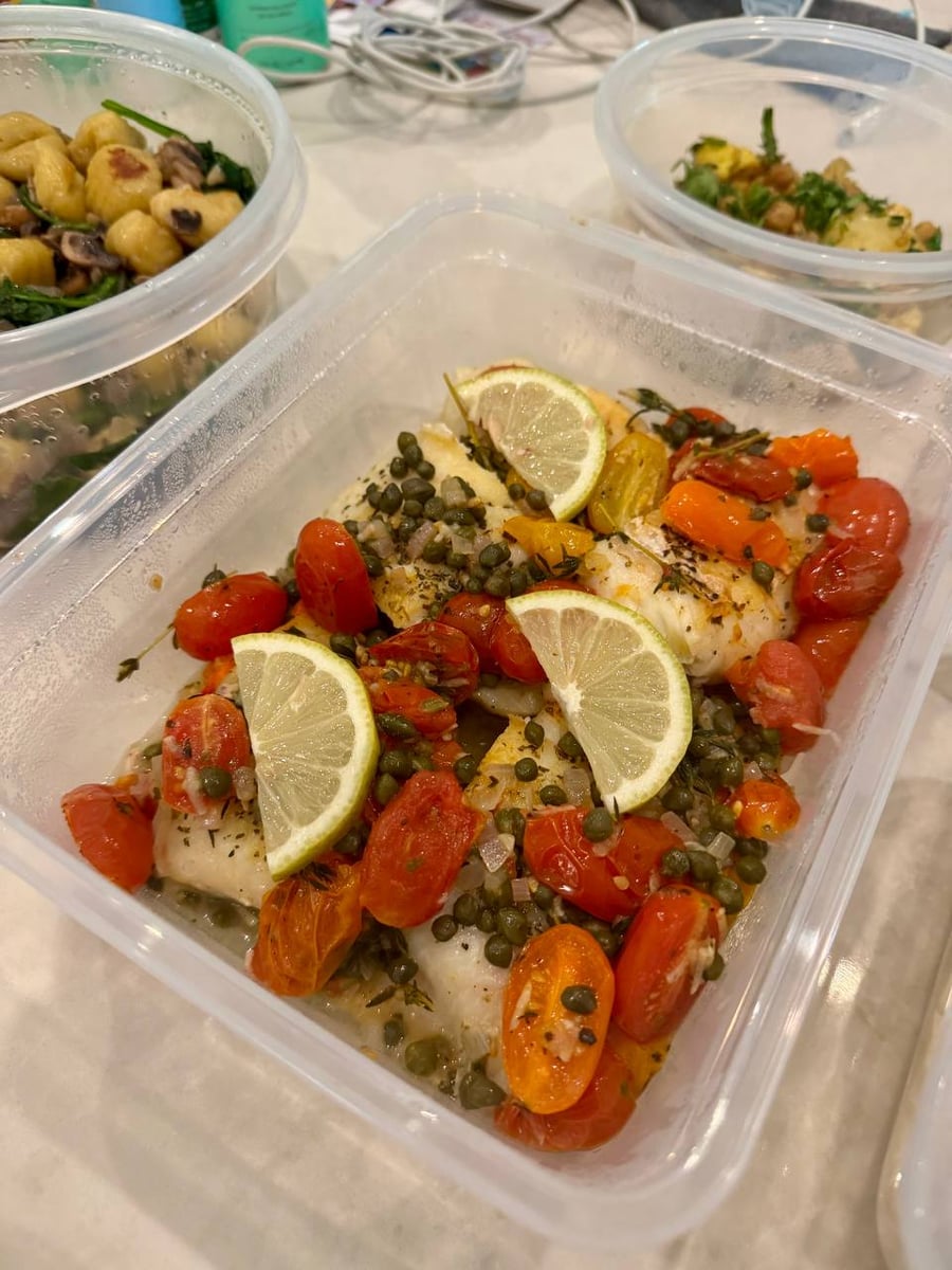 Capers and burst cherry tomatoes bury the halibut fillets under lemon wheels and thyme.