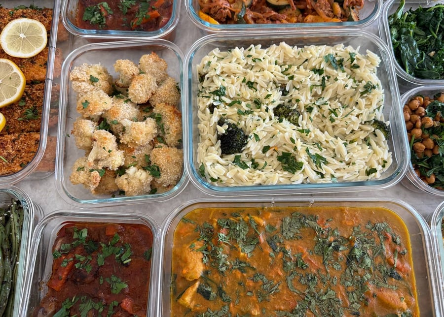 Thirteen containers cover the table: Burgundy beef, panko salmon, turmeric chicken stew, orzo, quinoa and greens.