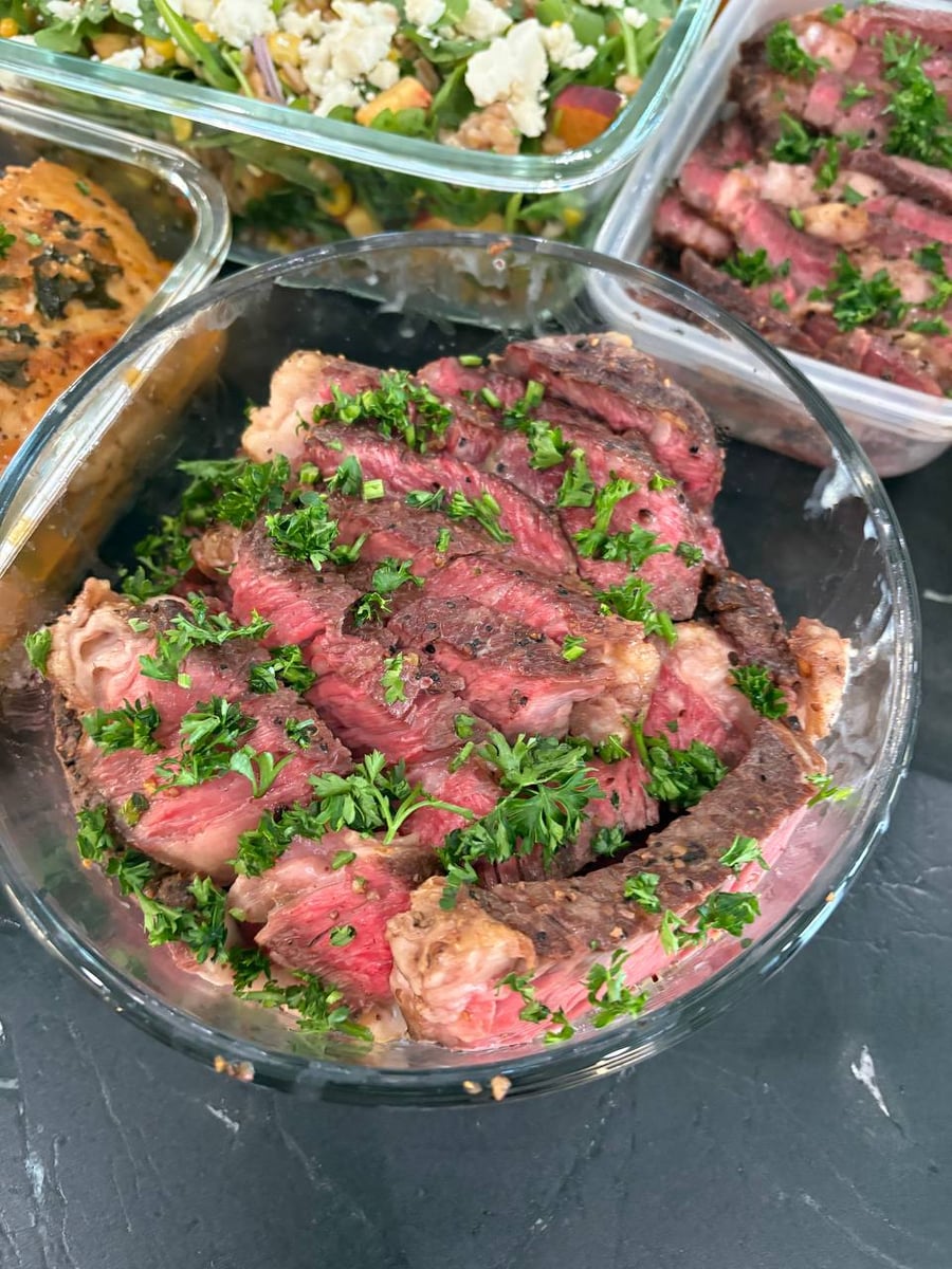 Rosemary ribeye slices show deep pink centres under charred edges, parsley scattered right across them.