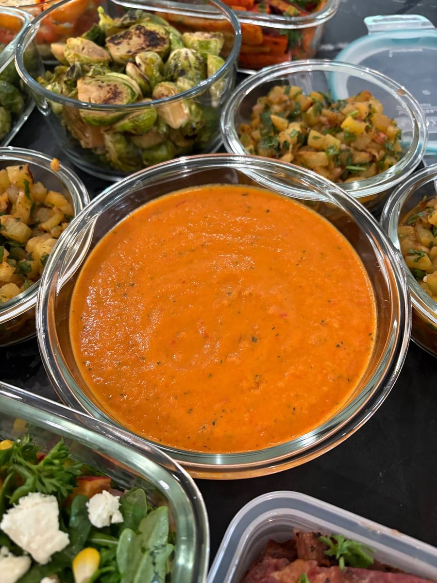 Smooth orange soup fills a wide bowl, pineapple salsa and balsamic brussel sprouts pressed in around it.