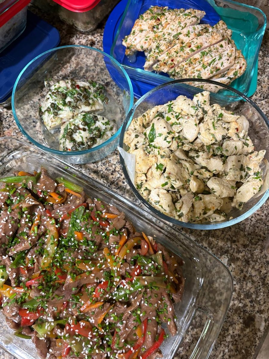 A collection of glass meal prep dishes featuring Mongolian beef with peppers, lemon caper swordfish steaks, and herb-marinated baked chicken breast bites.