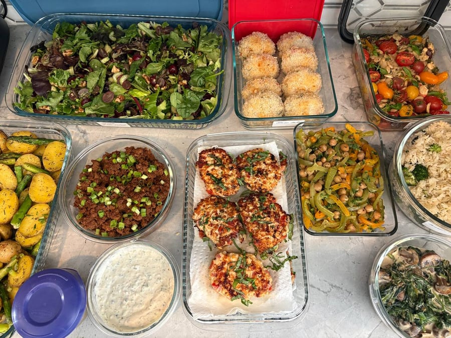 Basil ribbons drape the chicken dill mozzarella patties draining on paper, chickpeas and peppers behind.