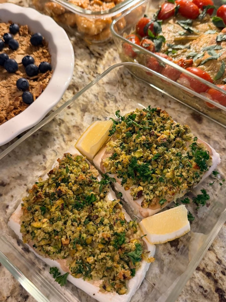 Pistachio and parsley crust baked onto halibut fillets, two lemon wedges tucked against the side.