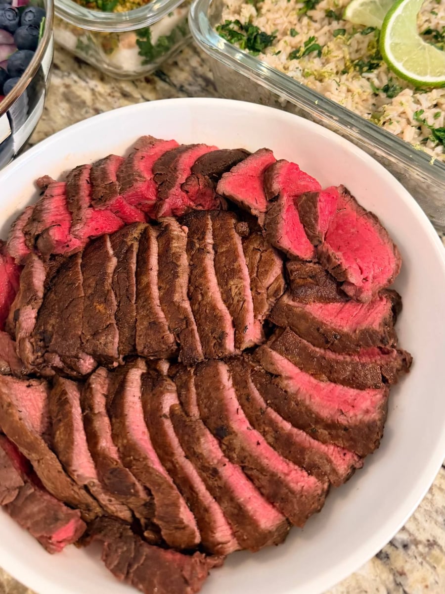 Filet mignon sliced thick to a deep rose centre, resting beside lime-flecked brown basmati.