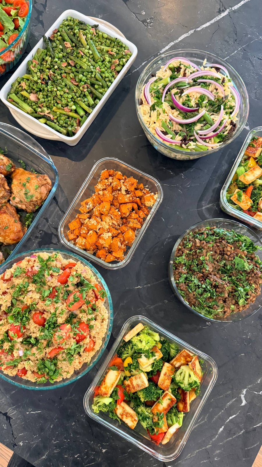 A variety of gourmet sides including seared asparagus with peas, brown rice orzo, quinoa salad, herbed sweet potatoes, and sauteed broccoli with paneer.