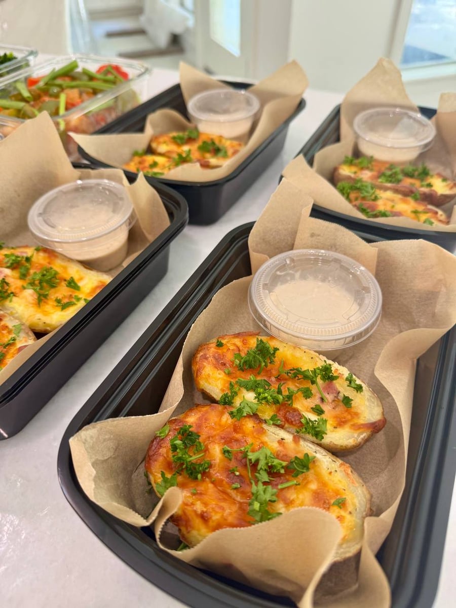Tomato basil chicken under melted mozzarella and whole basil leaves, stuffed potatoes to its right.