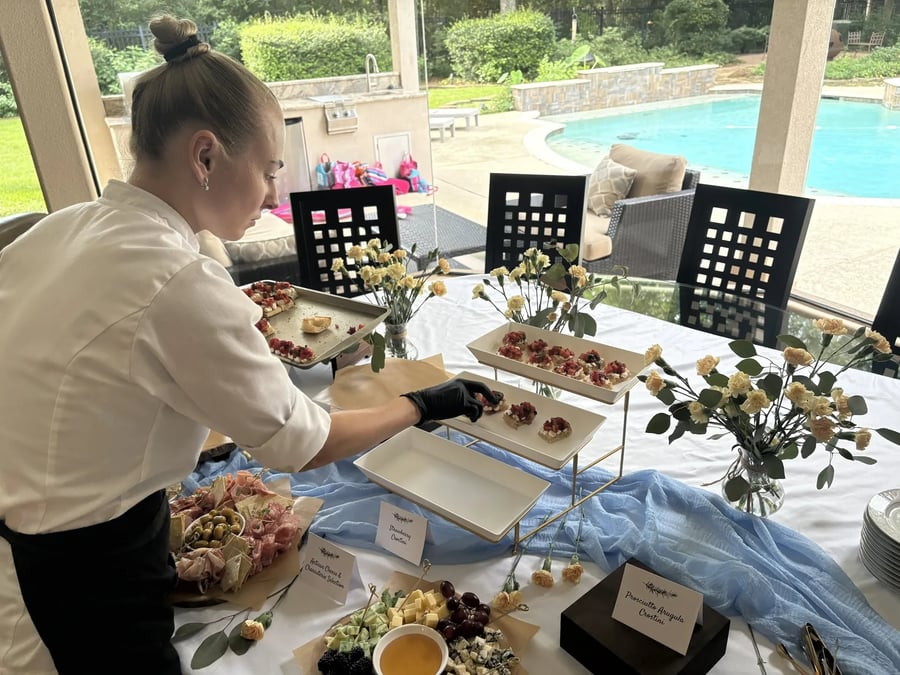 Chef Ana arranging an appetizer display beside a dining table in a client home