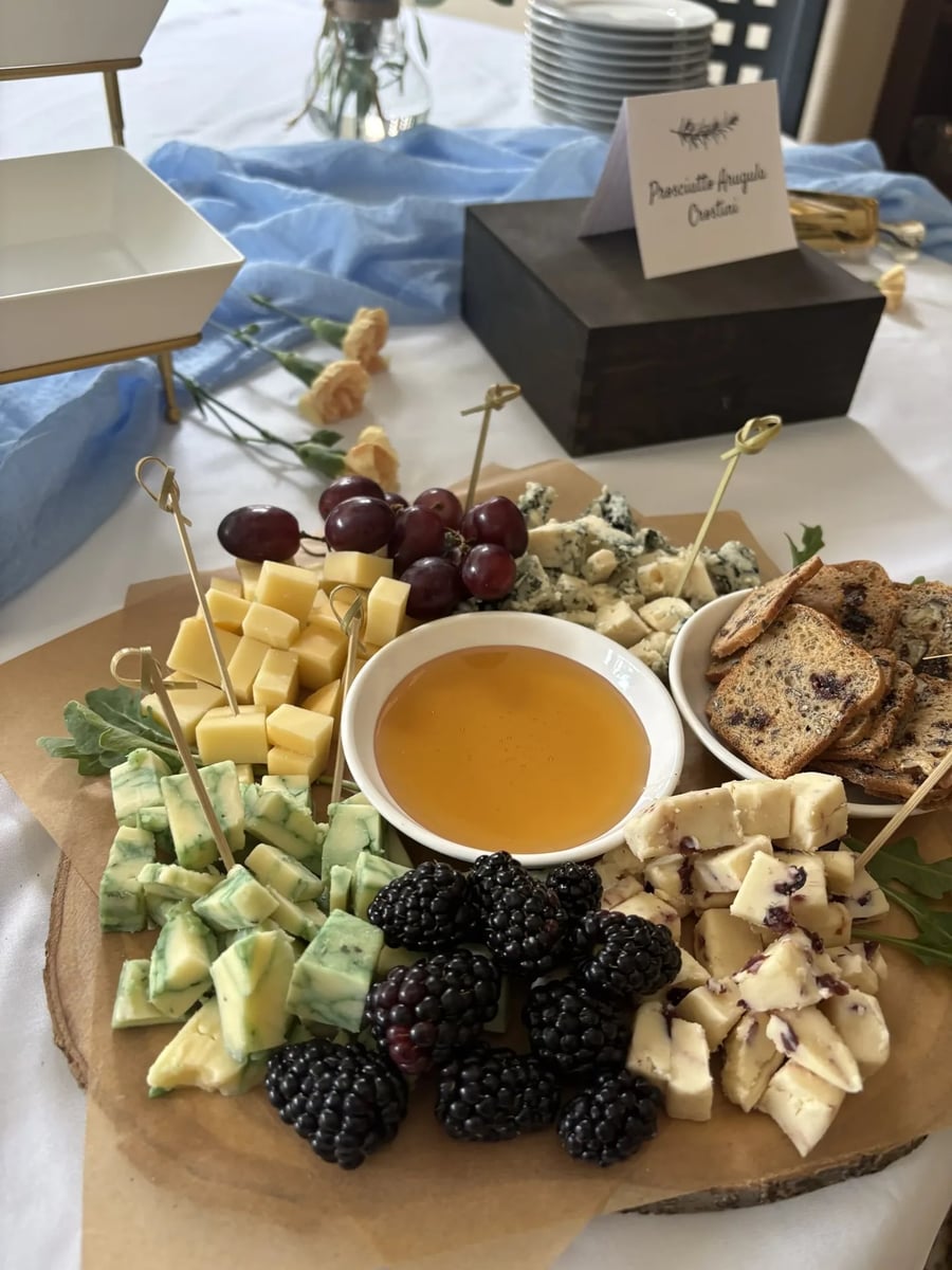 Artisan cheese and charcuterie selection — wide angle showing Prosciutto Crostini label in background.