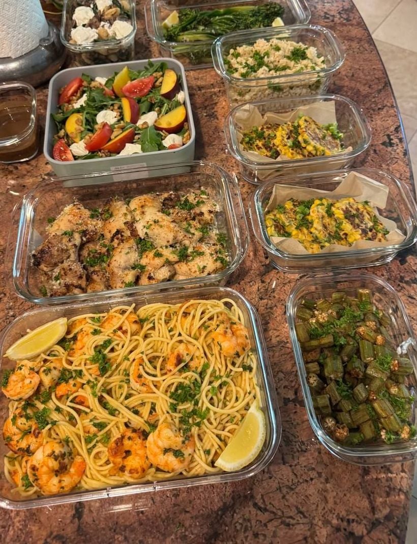Ten dishes fanned across a granite island, shrimp scampi spaghetti nearest the camera.