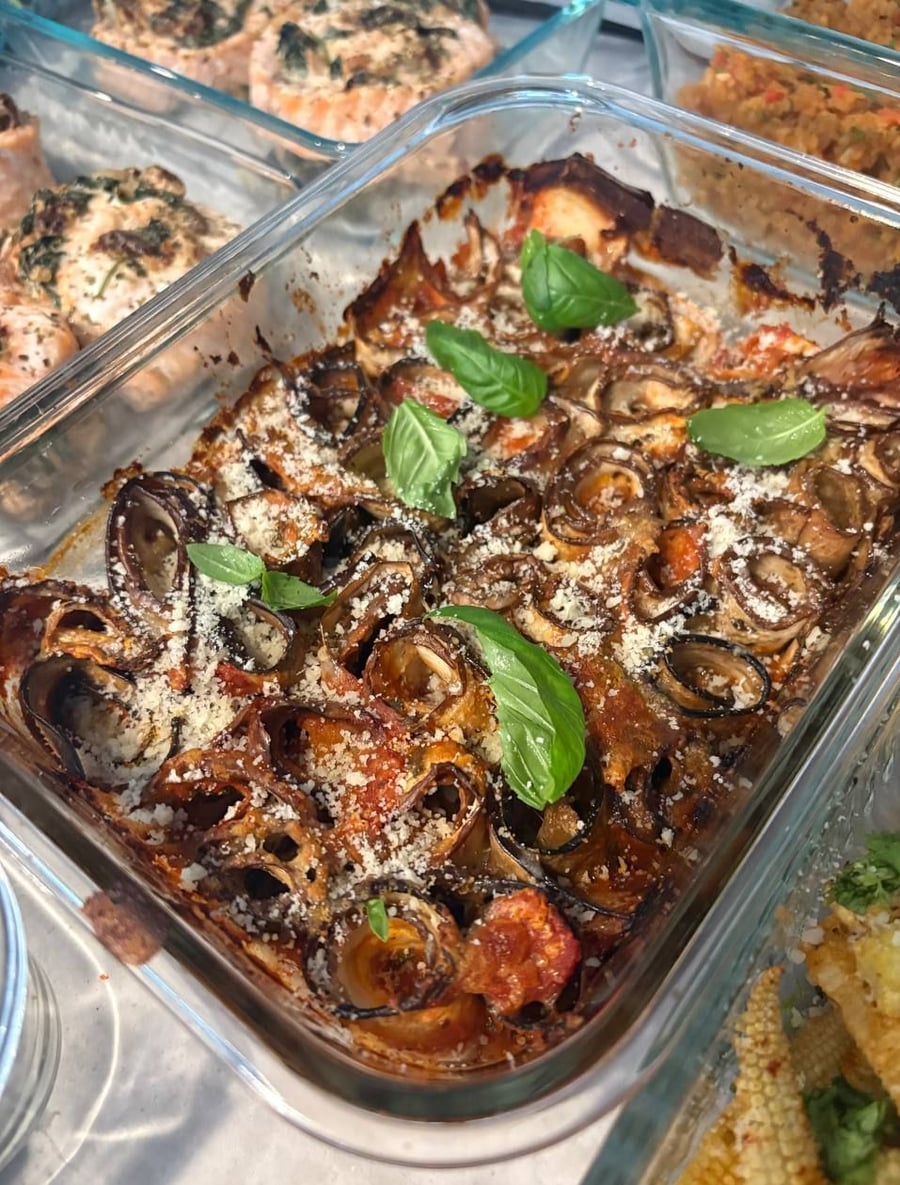 Nine dishes across a pale counter, salmon pinwheels and Greek beefsteaks holding the middle.