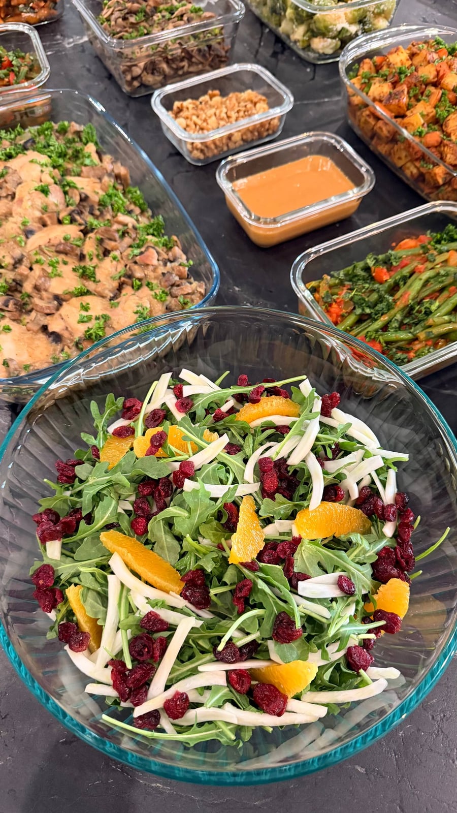 Shaved fennel, orange segments and dried cranberries piled over arugula in a glass bowl.