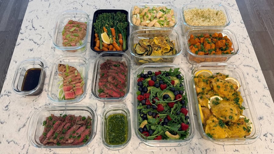 Thirteen dishes laid out in rows on white quartz, from the yellow saffron chicken to the tuna.