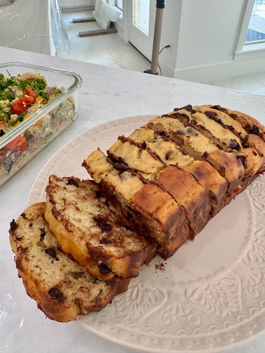 Chocolate-swirled banana bread pre-sliced on a scalloped plate, quinoa salad just behind.