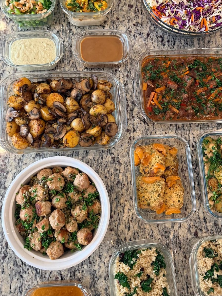 Capers and parsley pack around turkey picatta meatballs in a white bowl, potatoes just behind.