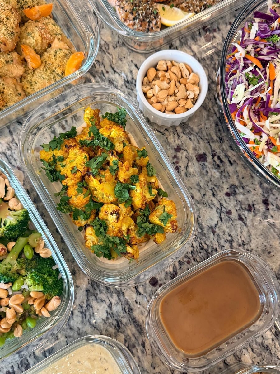 Turmeric-yellow cauliflower florets sit on a bed of hummus under a heap of chopped cilantro.