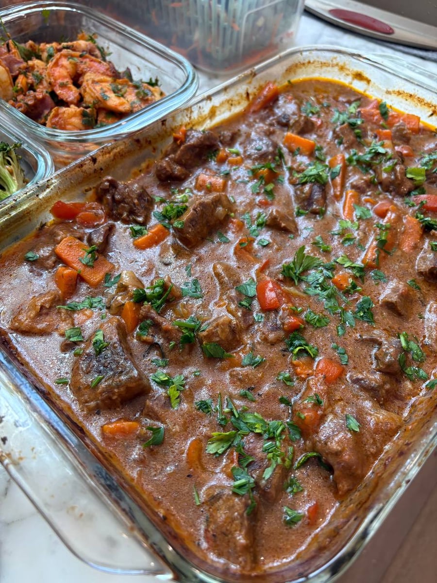 Chunks of beef and carrot batons surface through a thick red braise scattered with parsley.