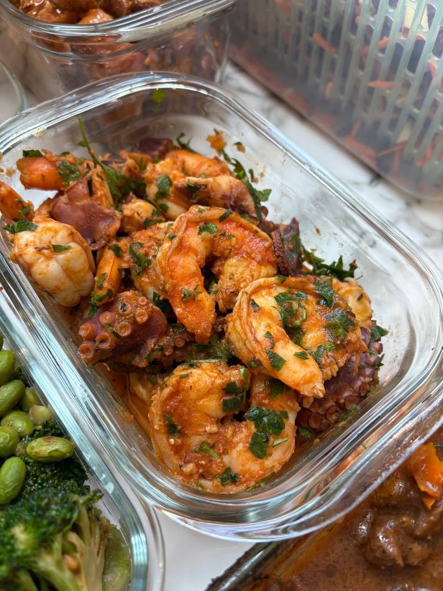Octopus tentacles curl between shrimp in a paprika oil, parsley chopped over the whole tub.