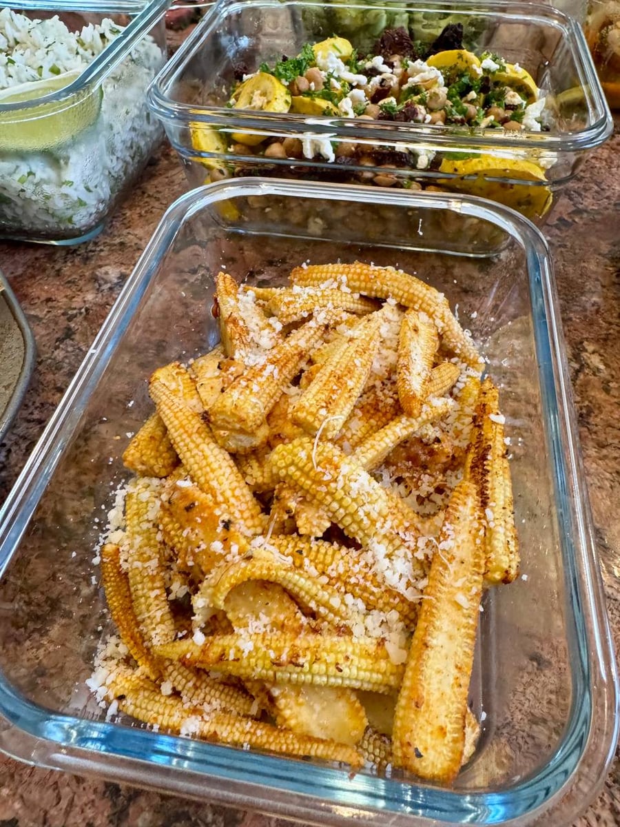 Whole baby corn cobs, charred at the tips, disappear under a heavy grating of parmesan.