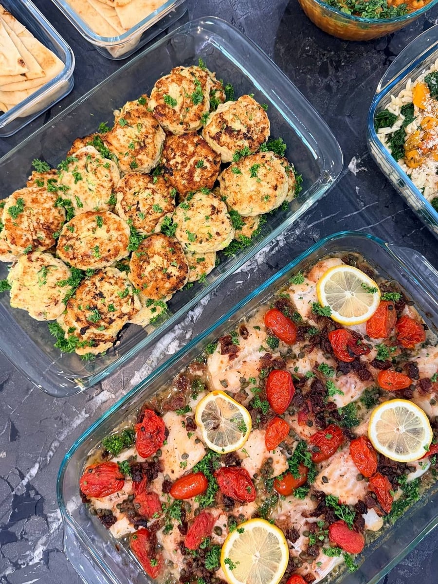 Blistered cherry tomatoes and capers cover white halibut fillets, three lemon wheels set on top.