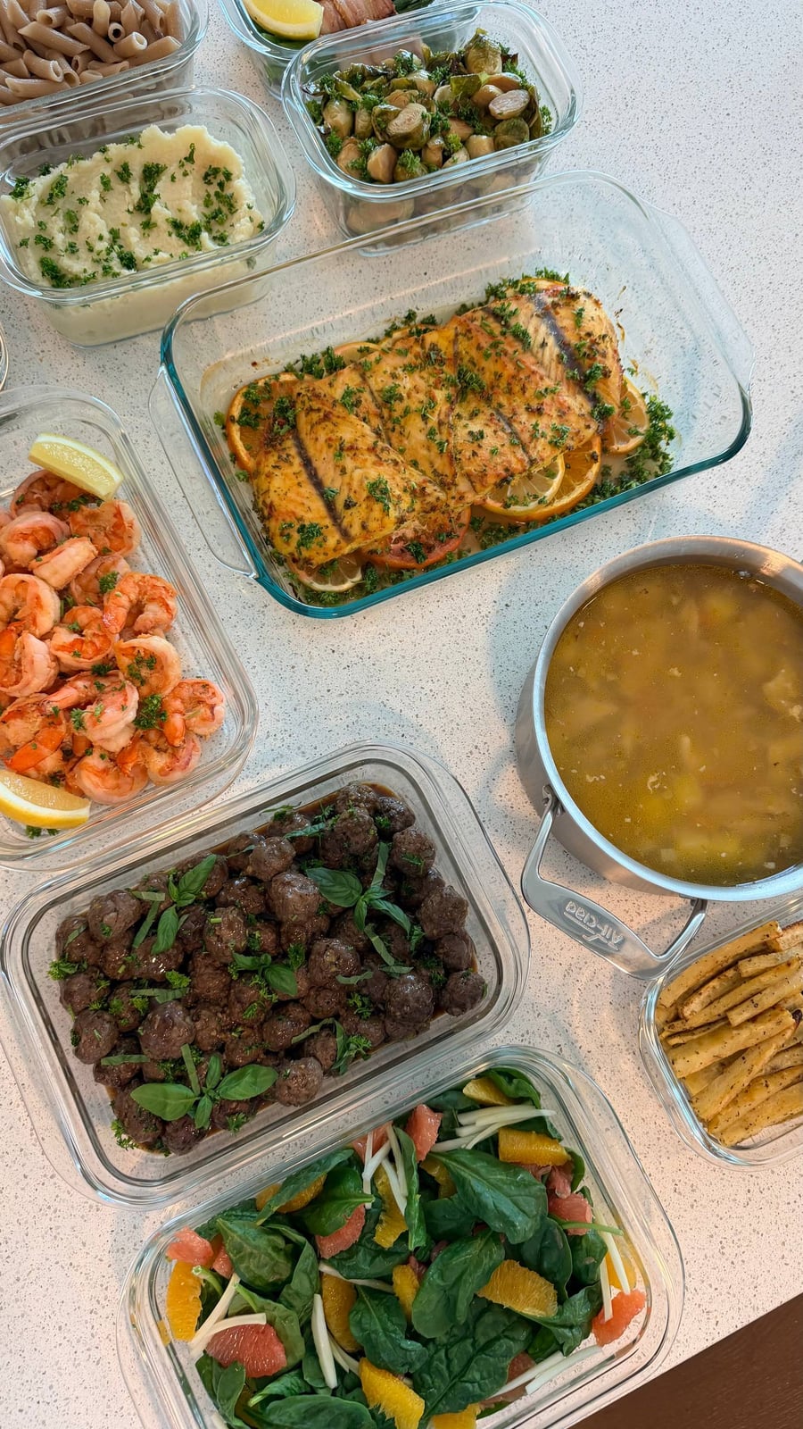 Barramundi fillets rest on orange wheels between elk meatballs, shrimp and a spinach grapefruit salad.