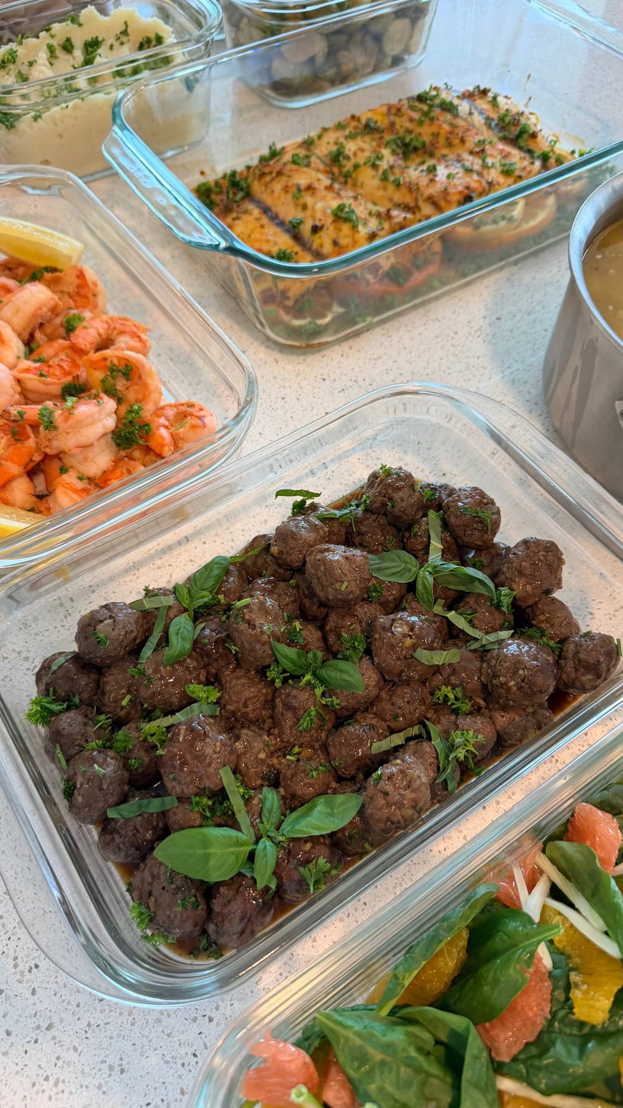 Basil leaves and parsley cover ground elk meatballs glazed dark in honey garlic sauce.
