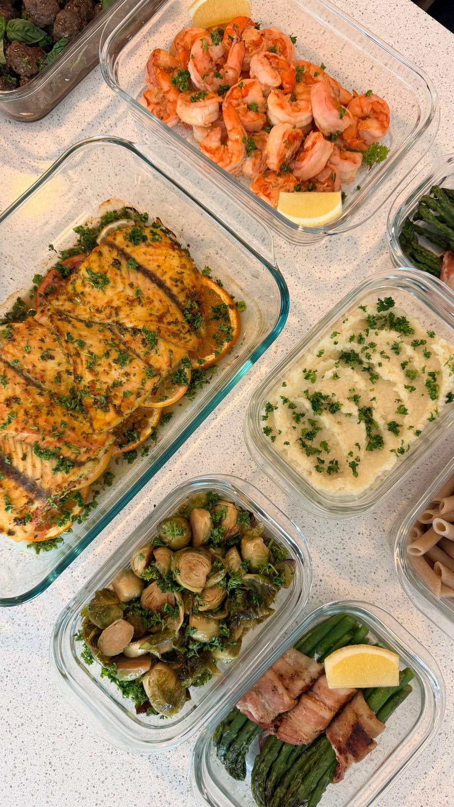 Peeled shrimp tossed in lemon garlic parsley crowd one tub, barramundi and brussels sprouts either side.