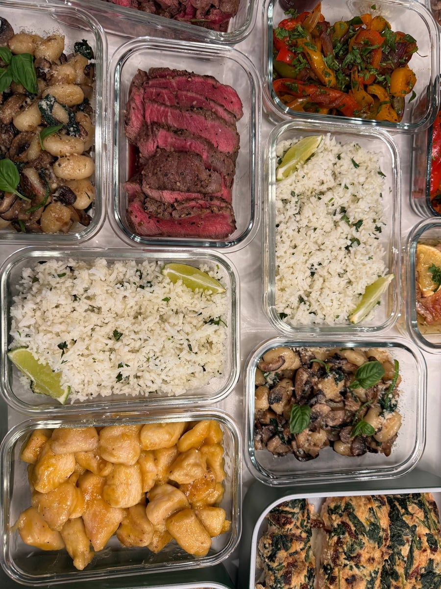 Medium rare filet mignon sits beside lime cilantro rice, orange chicken bites and browned paneer with broccoli.