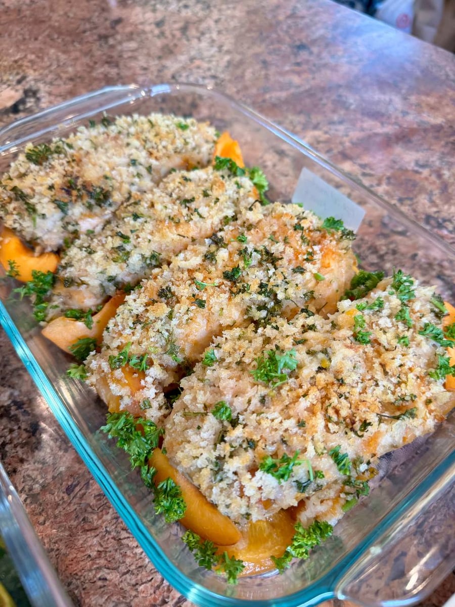 Herb flecked panko sits thick on chicken breasts, apricot slices tucked underneath and parsley around the edge.