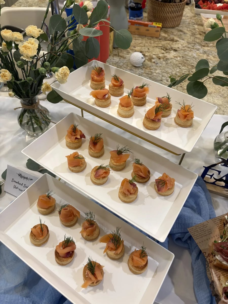 Smoked salmon vol-au-vent puff pastry shells with dill on a three-tier gold stand.
