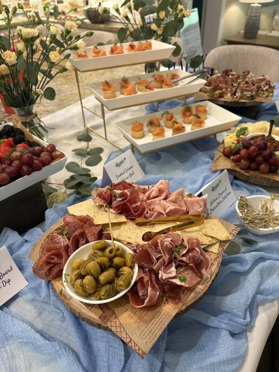 Artisan cheese and charcuterie board with rolled prosciutto, salami, mortadella, olives, and crackers.