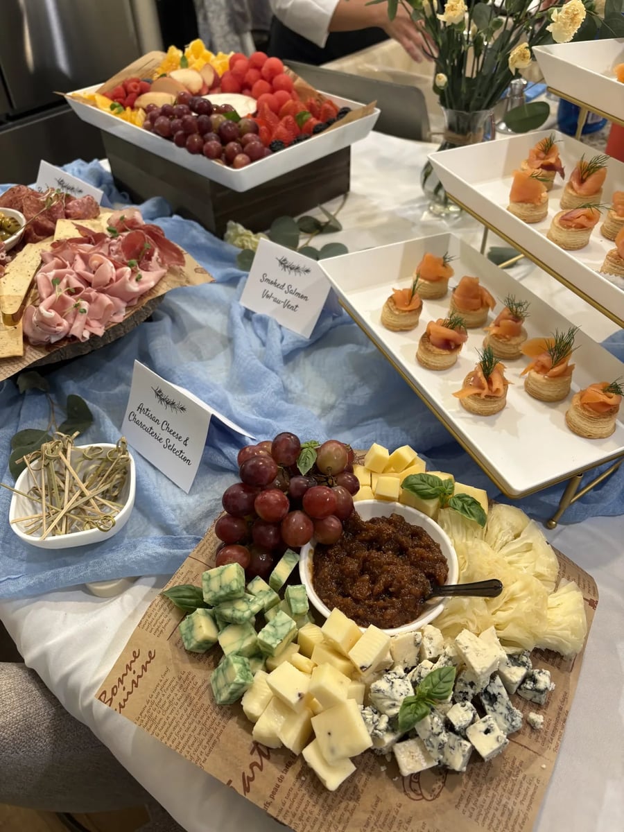 Cheese and charcuterie close-up with cubed cheeses, fig jam, red grapes, and charcuterie rosettes.