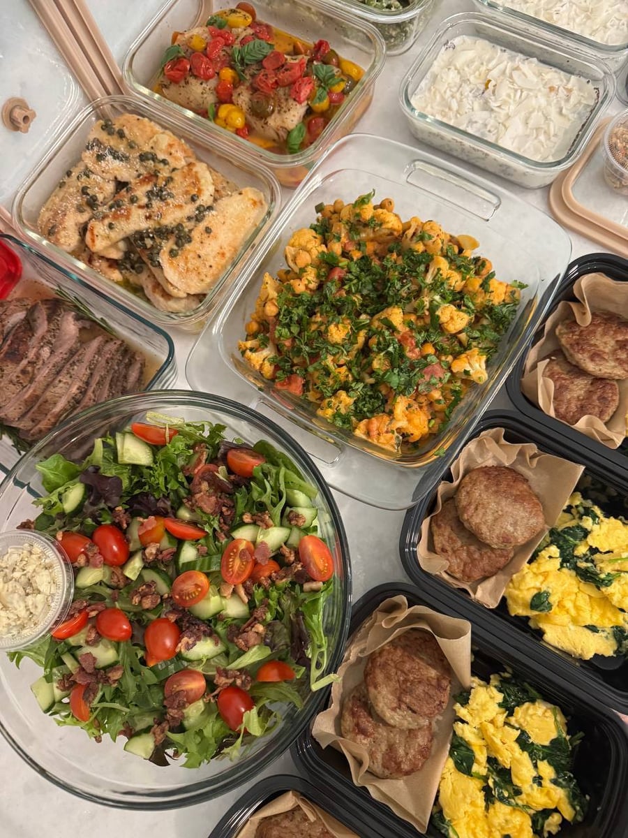 A variety of meal prep containers featuring chicken piccata, cauliflower chickpea curry, chopped salad, soft scramble with chicken patties, and roast beef.