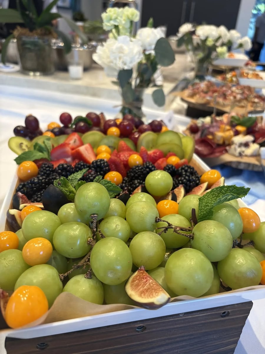 Fresh fruit board with green grapes, blackberries, citrus, figs, and strawberries.
