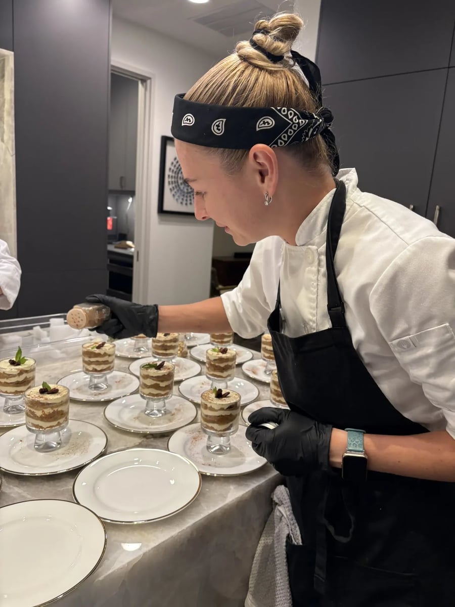 Chef plating individual spiced carrot cake verines in the kitchen before service.
