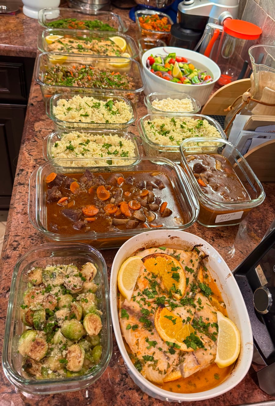 A collection of glass meal prep containers featuring orange-glazed salmon, beef stew with carrots, fluffy white rice, roasted Brussels sprouts, and fresh garden salad.