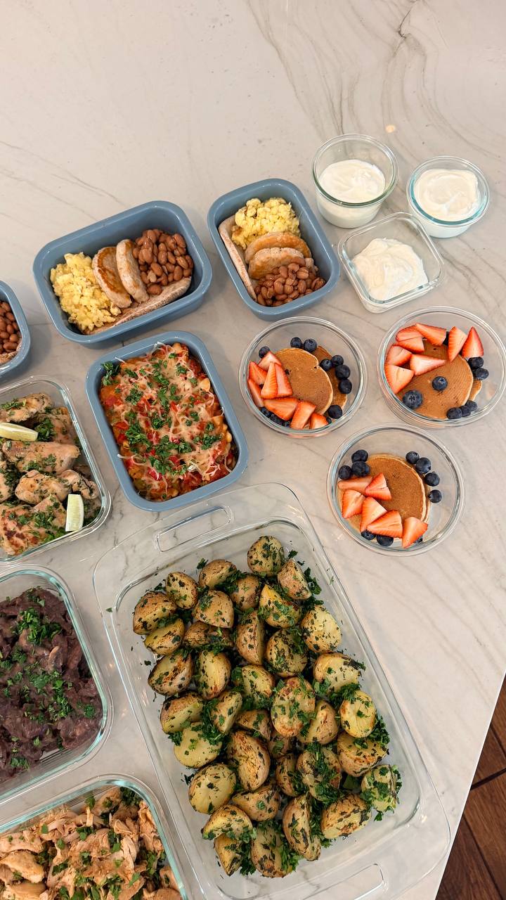 A variety of meal prep containers featuring protein oat pancakes, turkey patties with eggs, lime cilantro chicken, beef sirloin, and boiled gold potatoes.