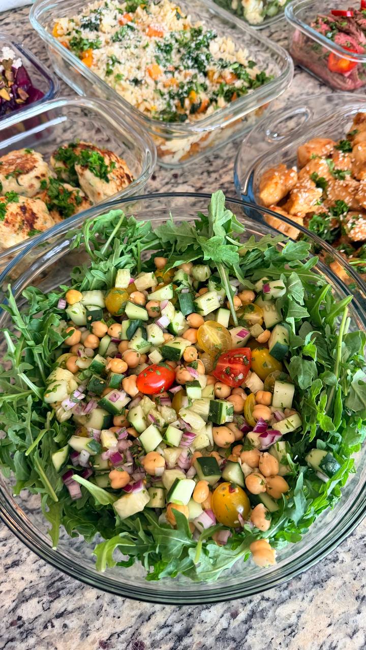 Mid-East chickpea salad with cucumbers, cherry tomatoes, and red onion served over fresh arugula, perfect for nutritious meal prep.