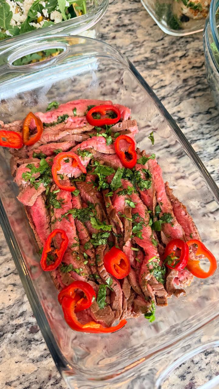 Thinly sliced Vietnamese skirt steak garnished with fresh chili rings and herbs, prepared for an elegant private chef dinner.