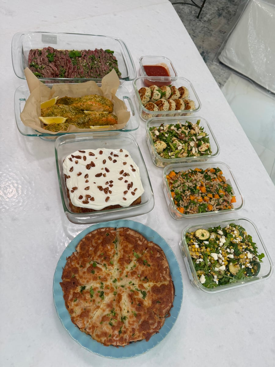 A variety of glass containers holding flank steak, pesto salmon, turkey fritters, roasted vegetables, orzo, salads, and scrambled egg tortilla pockets.