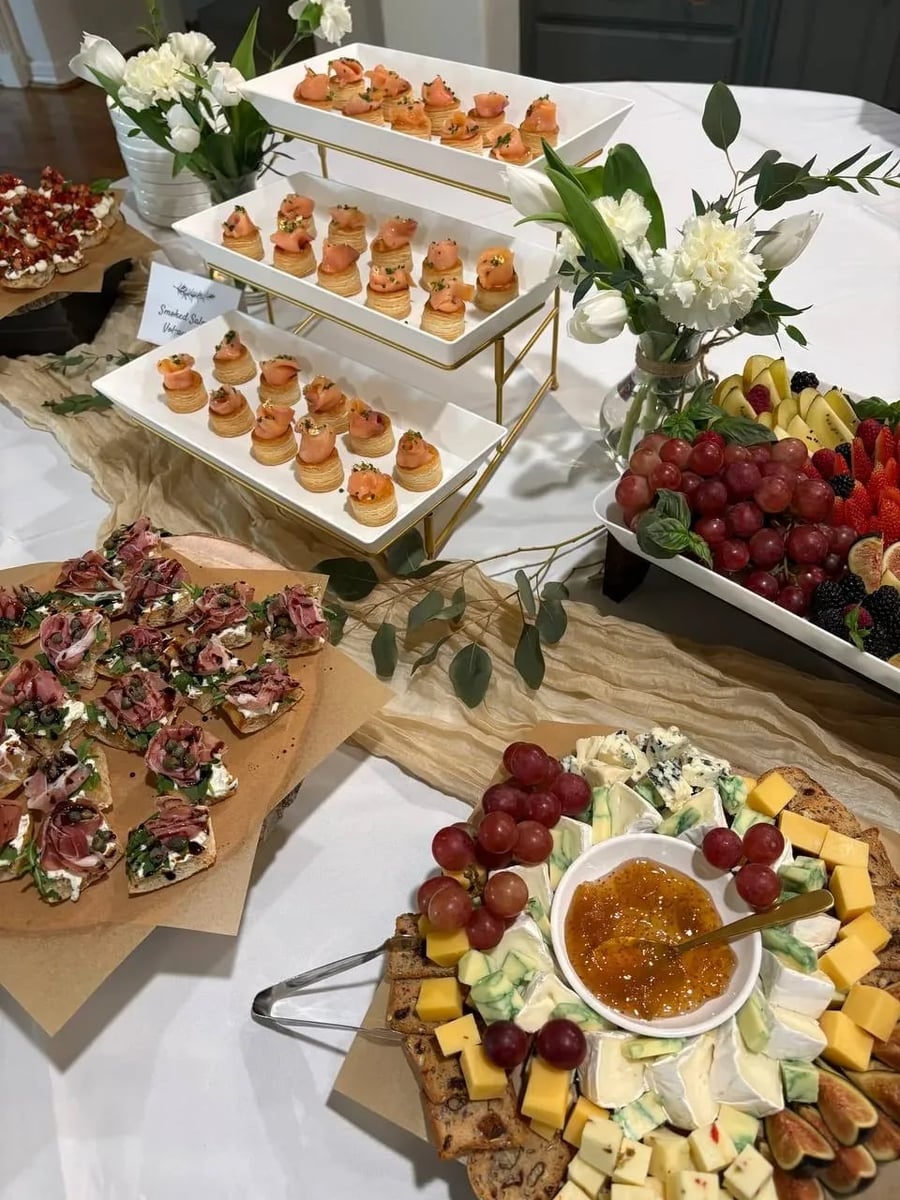 Full appetizer display: smoked salmon vol-au-vents on tiered stand, prosciutto crostini, cheese board, and fruit platter.