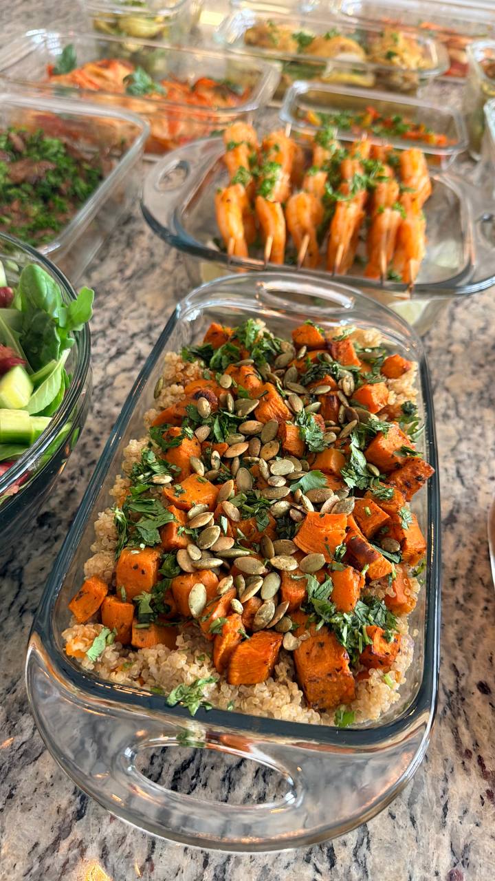 A container filled with fluffy cilantro quinoa topped with cubed roasted sweet potatoes, fresh chopped cilantro, and toasted pumpkin seeds.