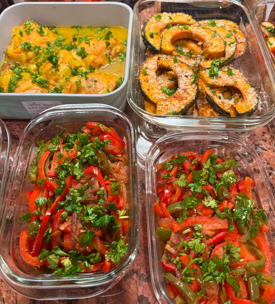 Four glass storage containers holding tender saffron chicken, parmesan-topped roasted acorn squash, and colorful sautéed bell peppers garnished with fresh chopped cilantro.
