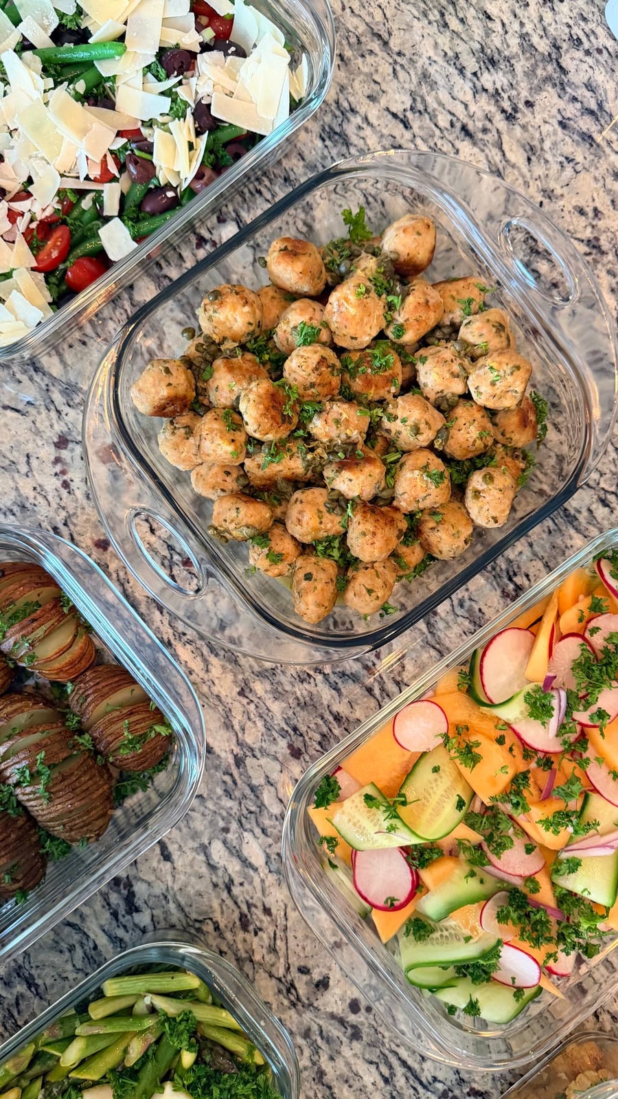 Glass containers featuring golden chicken picatta meatballs, crispy rosemary hasselback potatoes, and a refreshing melon, cucumber, and radish salad with fresh herbs.