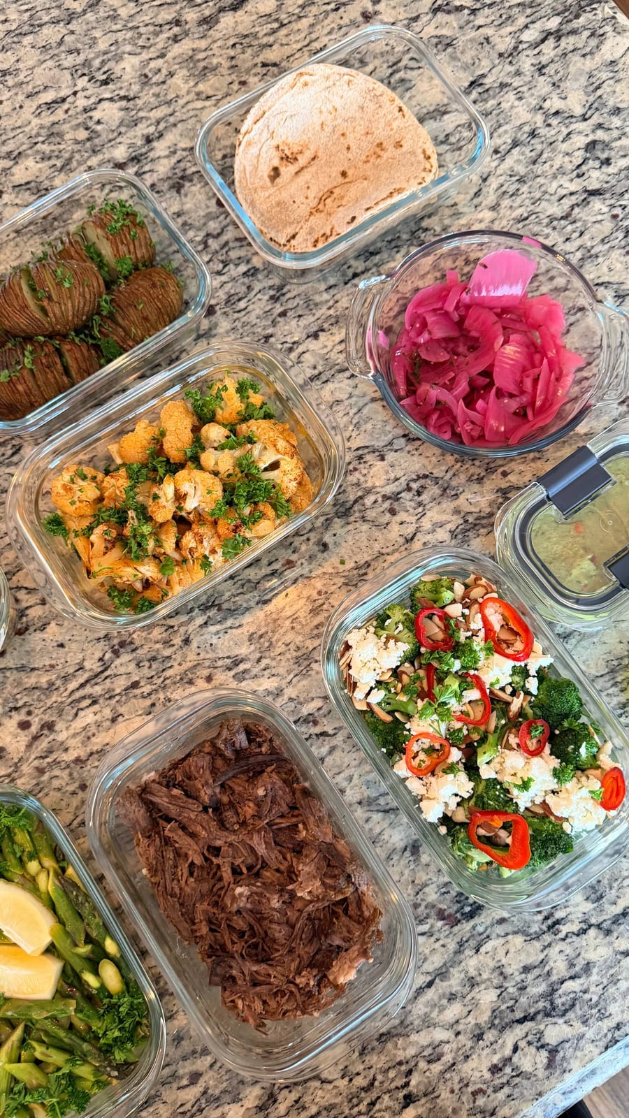 Glass containers featuring Mexican shredded beef, whole wheat tortillas, pickled onions, roasted honey lime cauliflower, hasselback potatoes, broccoli, and ginger asparagus stir-fry.