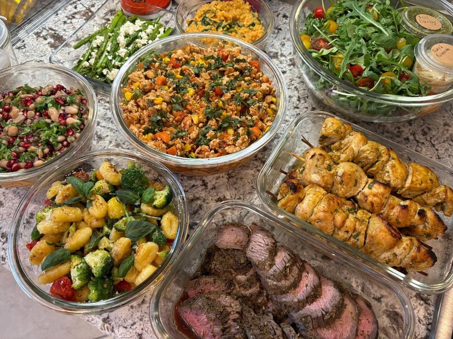 Full spread of prepared meals: beef, chicken skewers, salads, gnocchi