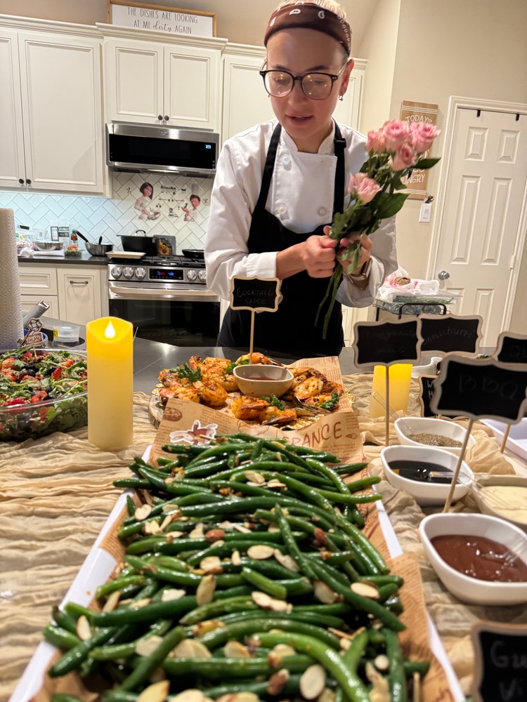 Chef Ana arranging flowers on the buffet table with green beans in foreground